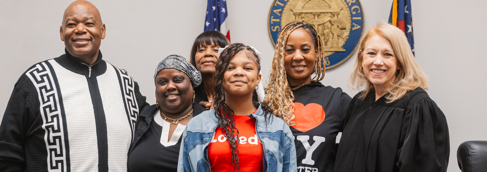 Mother and daughter gather at adoption day with loved ones and judge.